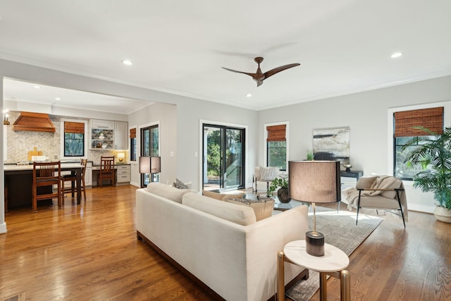 living room with ceiling fan, recessed lighting, crown molding, and wood finished floors