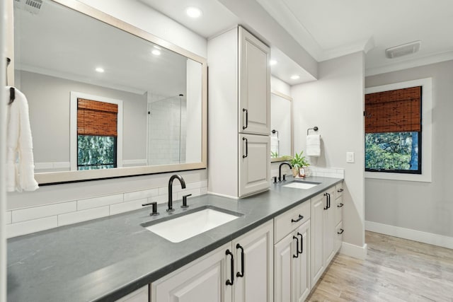 full bathroom featuring wood finished floors, ornamental molding, a sink, and visible vents