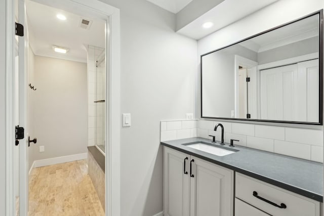 bathroom with tasteful backsplash, baseboards, wood finished floors, vanity, and recessed lighting