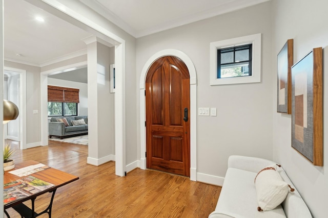 entryway featuring light wood-type flooring, arched walkways, and crown molding