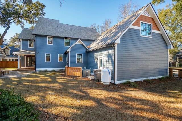 rear view of house featuring a shingled roof, central AC, and a yard