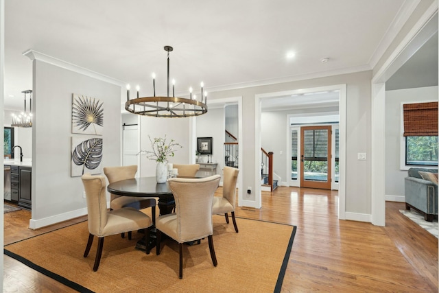 dining room with crown molding, light wood-style floors, and a notable chandelier