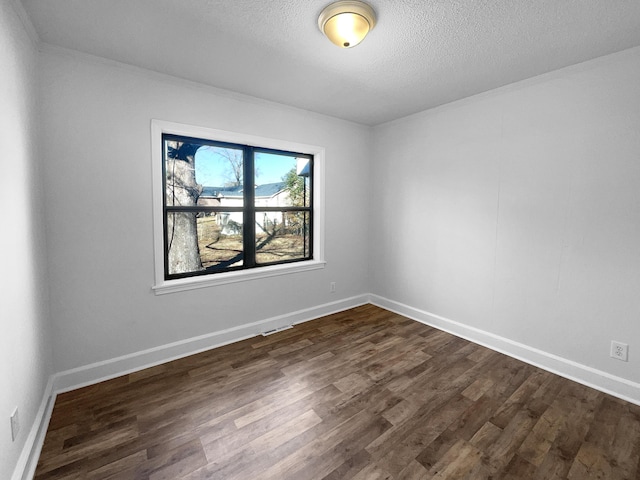 spare room with a textured ceiling and dark hardwood / wood-style floors