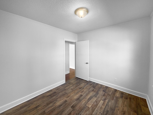 spare room featuring a textured ceiling and dark wood-type flooring