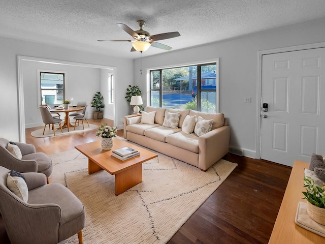 living room with ceiling fan, a textured ceiling, and dark hardwood / wood-style floors