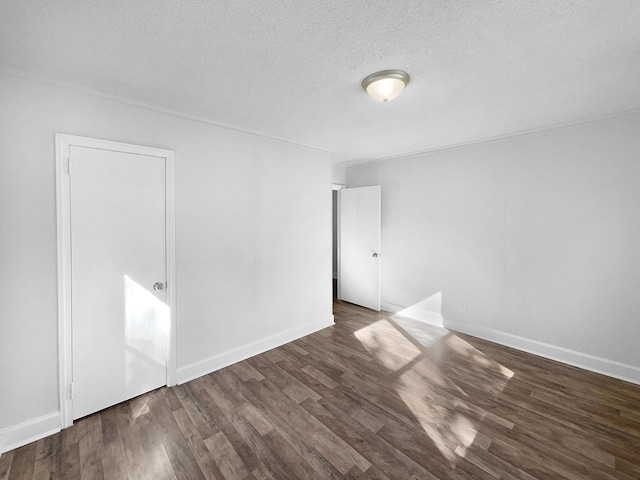 empty room with a textured ceiling and dark wood-type flooring