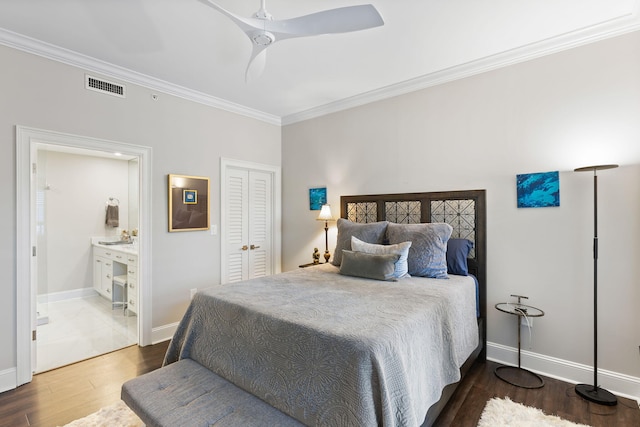 bedroom featuring baseboards, ensuite bathroom, ornamental molding, visible vents, and wood finished floors