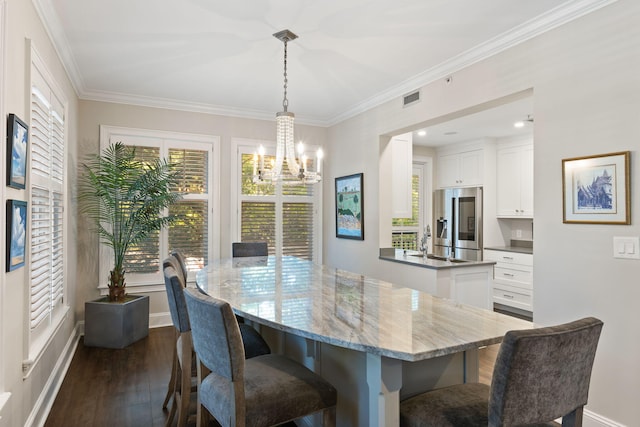 dining space featuring baseboards, visible vents, dark wood finished floors, crown molding, and a notable chandelier