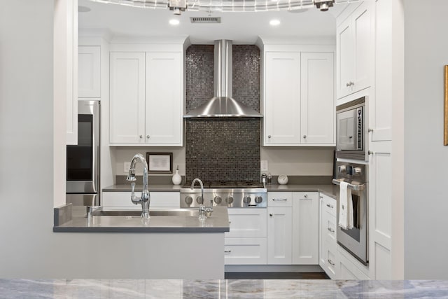 kitchen featuring tasteful backsplash, visible vents, wall chimney exhaust hood, white cabinetry, and appliances with stainless steel finishes