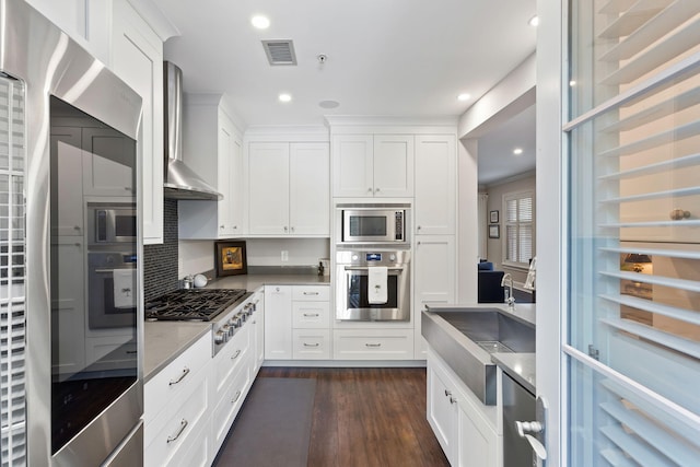 kitchen featuring visible vents, white cabinetry, wall chimney exhaust hood, appliances with stainless steel finishes, and dark wood-style floors