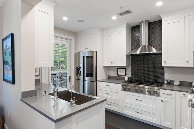 kitchen with visible vents, white cabinetry, wall chimney exhaust hood, backsplash, and appliances with stainless steel finishes