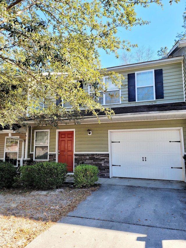 townhome / multi-family property featuring a garage, concrete driveway, and stone siding