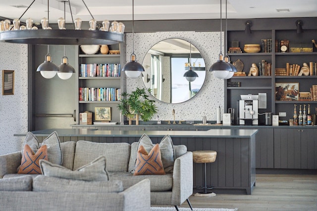 bar with wood-type flooring, built in features, and decorative light fixtures