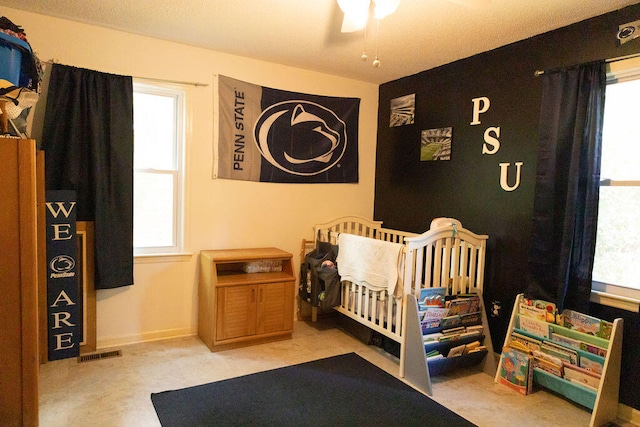 bedroom with a nursery area and ceiling fan