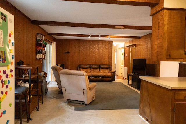 living room with rail lighting, wood walls, beamed ceiling, and light carpet