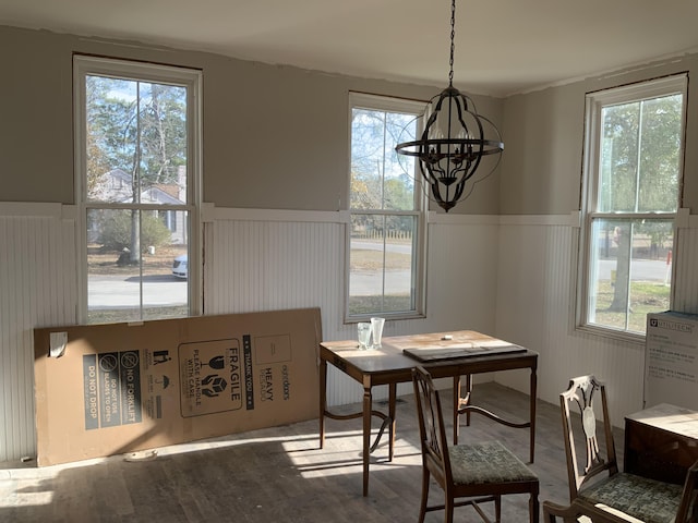 dining room with wood-type flooring, a wealth of natural light, and a notable chandelier