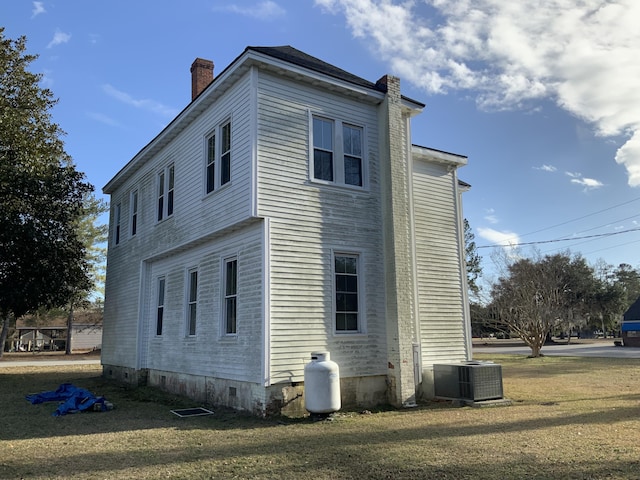 view of side of home featuring central AC and a lawn