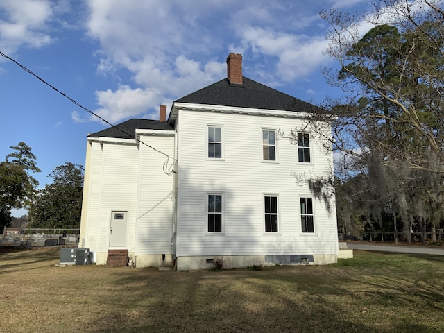 back of house featuring central AC and a lawn