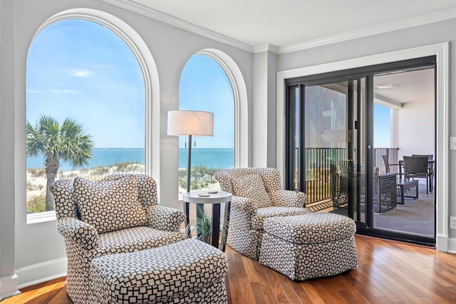 sitting room with crown molding, a water view, baseboards, and wood-type flooring