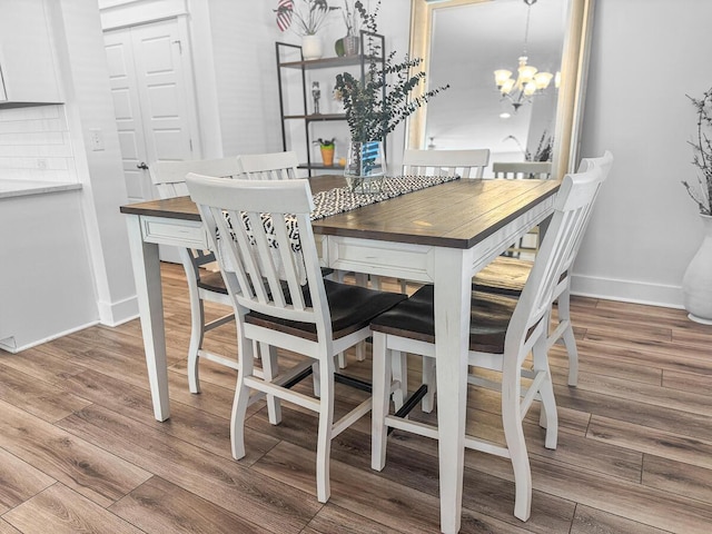 dining room featuring an inviting chandelier, baseboards, and wood finished floors