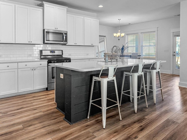 kitchen with stainless steel appliances, an island with sink, and white cabinetry