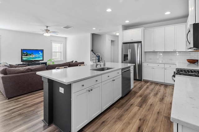 kitchen featuring appliances with stainless steel finishes, a kitchen island with sink, and white cabinetry