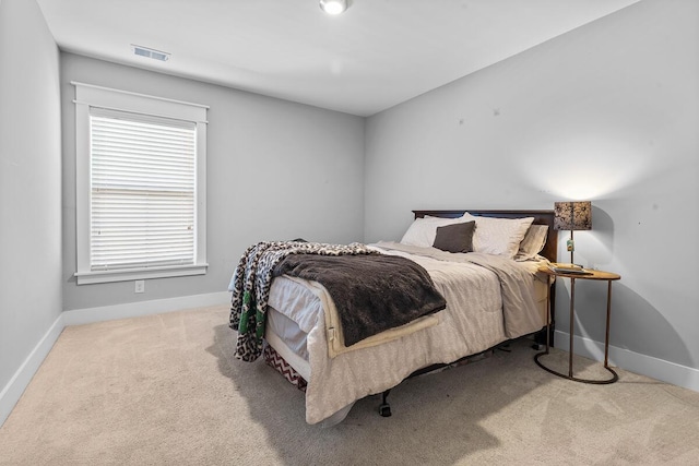 bedroom with visible vents, light carpet, and baseboards