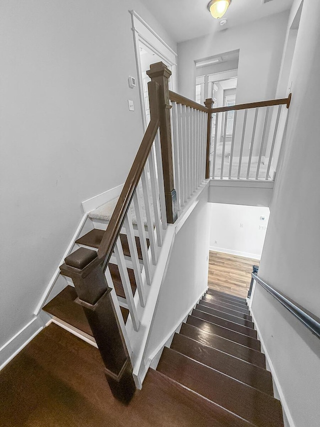 staircase featuring wood finished floors and baseboards