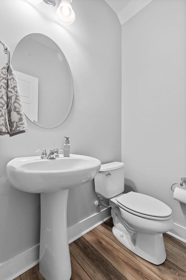 bathroom with wood finished floors, toilet, and baseboards