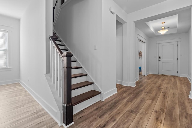 foyer featuring baseboards, stairway, and wood finished floors