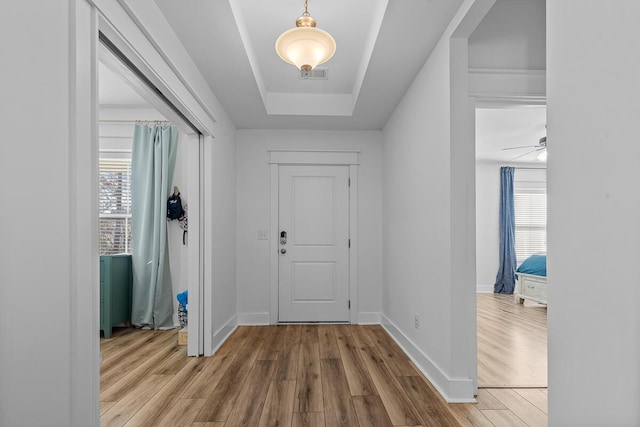 foyer entrance featuring a wealth of natural light, visible vents, a tray ceiling, and wood finished floors