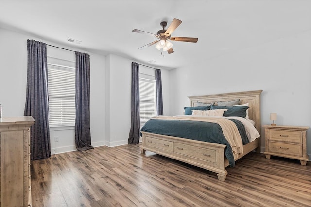 bedroom featuring a ceiling fan, baseboards, visible vents, and wood finished floors