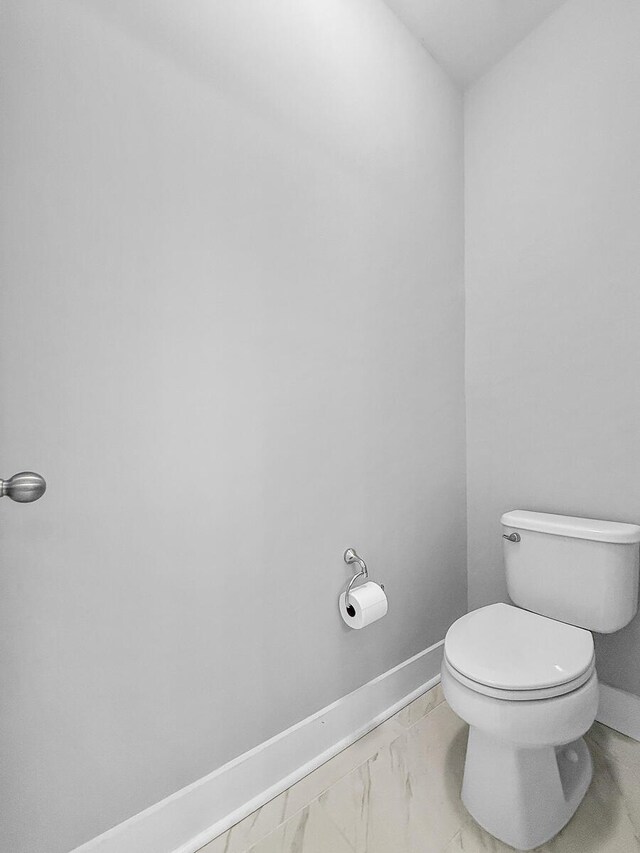 bathroom with marble finish floor, baseboards, and toilet