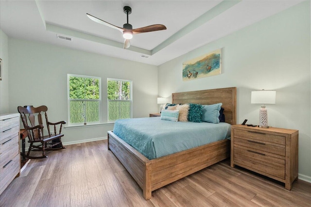 bedroom with a tray ceiling, ceiling fan, and hardwood / wood-style floors