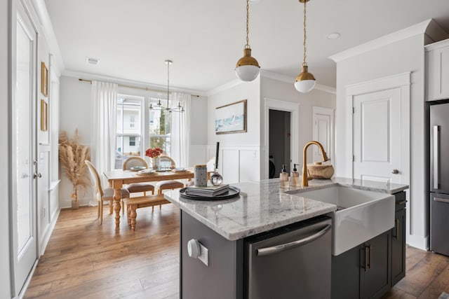 kitchen featuring stainless steel appliances, a center island with sink, sink, and crown molding