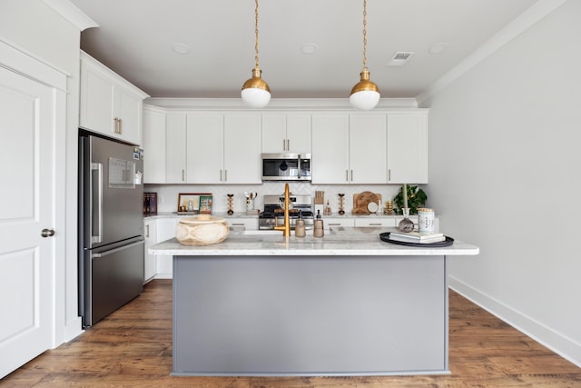 kitchen featuring light stone counters, hanging light fixtures, an island with sink, white cabinets, and appliances with stainless steel finishes