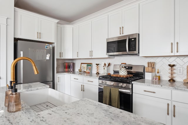 kitchen with stainless steel appliances, white cabinetry, backsplash, and light stone countertops