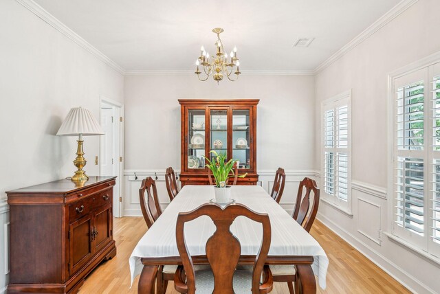 174 Revetment Ln, Mount Pleasant, SC 29464 - dining room featuring light wood-style flooring, a chandelier, wainscoting, and ornamental molding