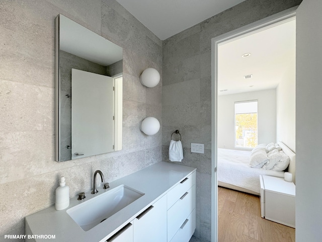 bathroom featuring hardwood / wood-style floors, vanity, backsplash, and tile walls