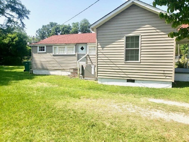 rear view of property featuring cooling unit and a yard