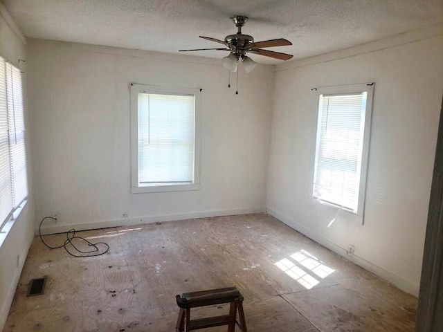 empty room featuring a healthy amount of sunlight, ceiling fan, and a textured ceiling