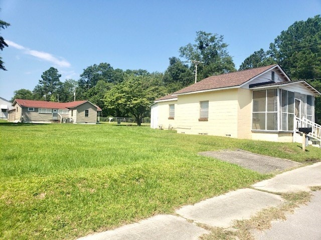 view of side of home with a sunroom and a lawn