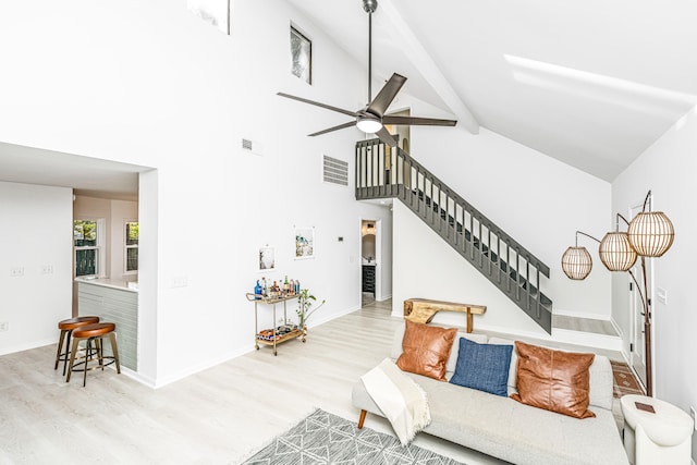 living room featuring beamed ceiling, high vaulted ceiling, light hardwood / wood-style flooring, and ceiling fan