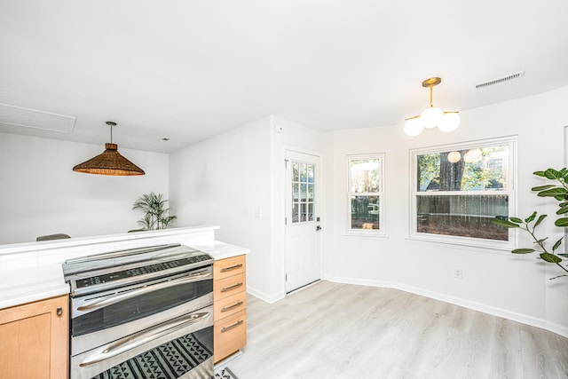 kitchen featuring light brown cabinets, stainless steel stove, light hardwood / wood-style floors, and decorative light fixtures