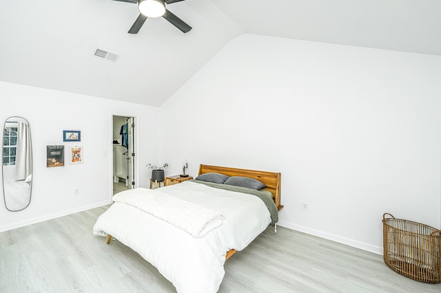 bedroom featuring a walk in closet, light hardwood / wood-style flooring, vaulted ceiling, and ceiling fan