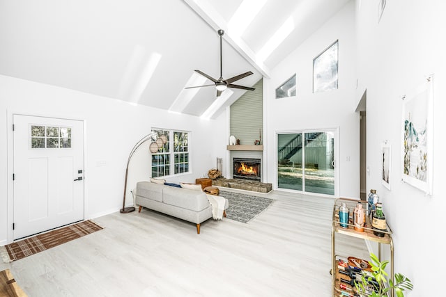 living room with light hardwood / wood-style flooring, high vaulted ceiling, ceiling fan, and a healthy amount of sunlight