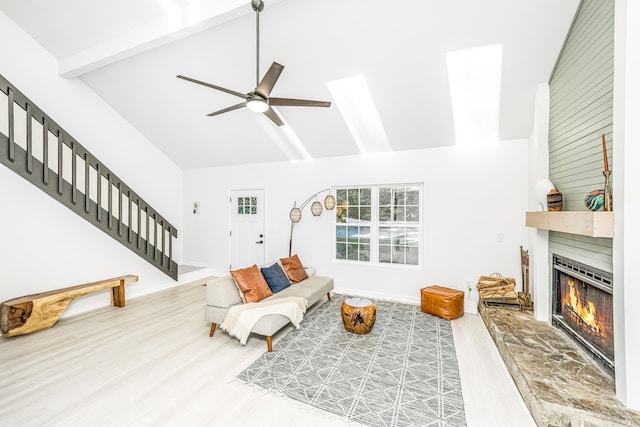 living room featuring a large fireplace, ceiling fan, wood-type flooring, high vaulted ceiling, and beamed ceiling