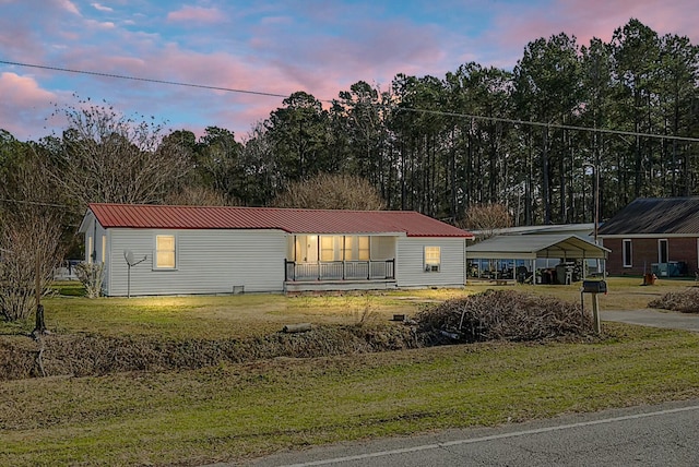 manufactured / mobile home featuring a carport and a yard