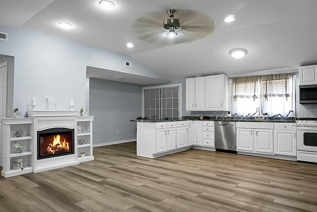 kitchen featuring appliances with stainless steel finishes, sink, white cabinetry, light hardwood / wood-style floors, and lofted ceiling