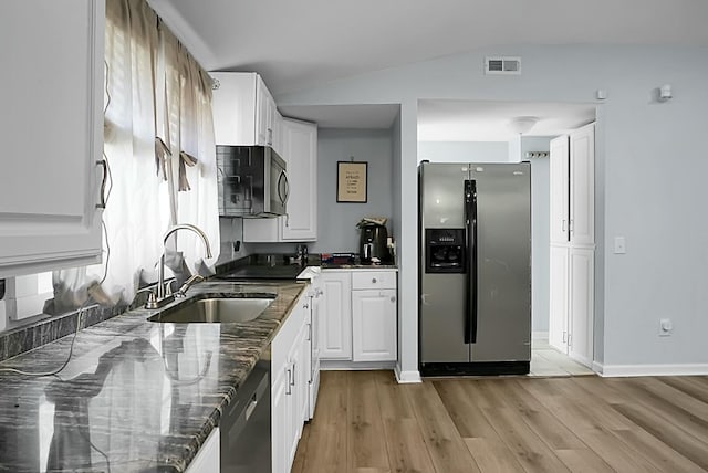 kitchen featuring sink, white cabinetry, dark stone countertops, lofted ceiling, and stainless steel appliances